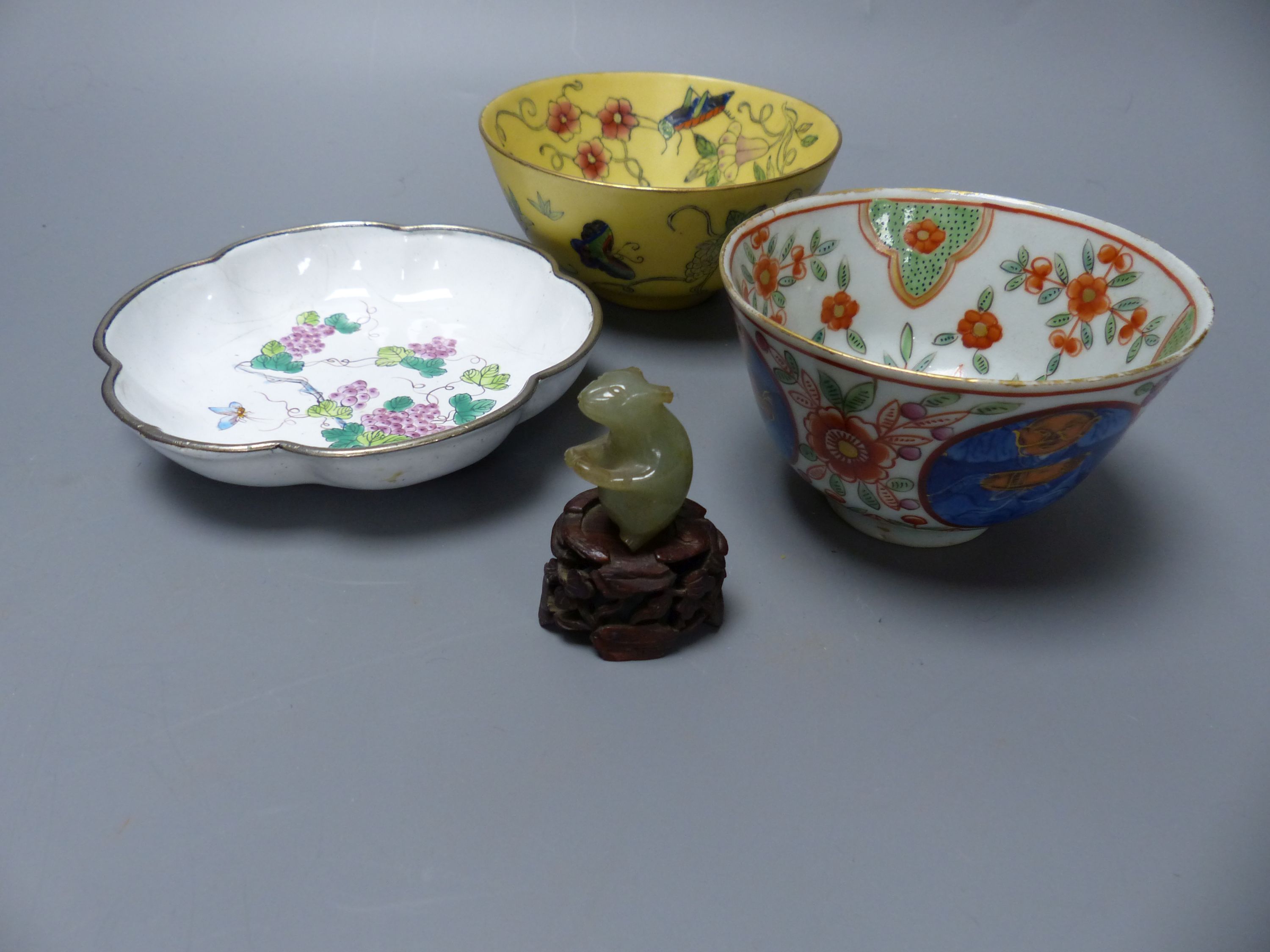 A carved jade mouse on associated hardwood stand, three pieces of Oriental porcelain including an enamel dish and two tea bowls, larges